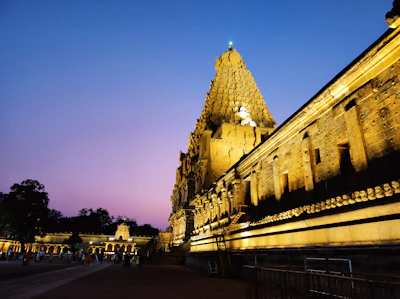 A historic temple glowing warmly in the golden hour light with visitors admiring it.