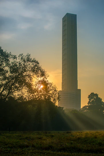A sleek corporate office building silhouette with a rising sun against a blue background, symbolizing new beginnings and trust.
