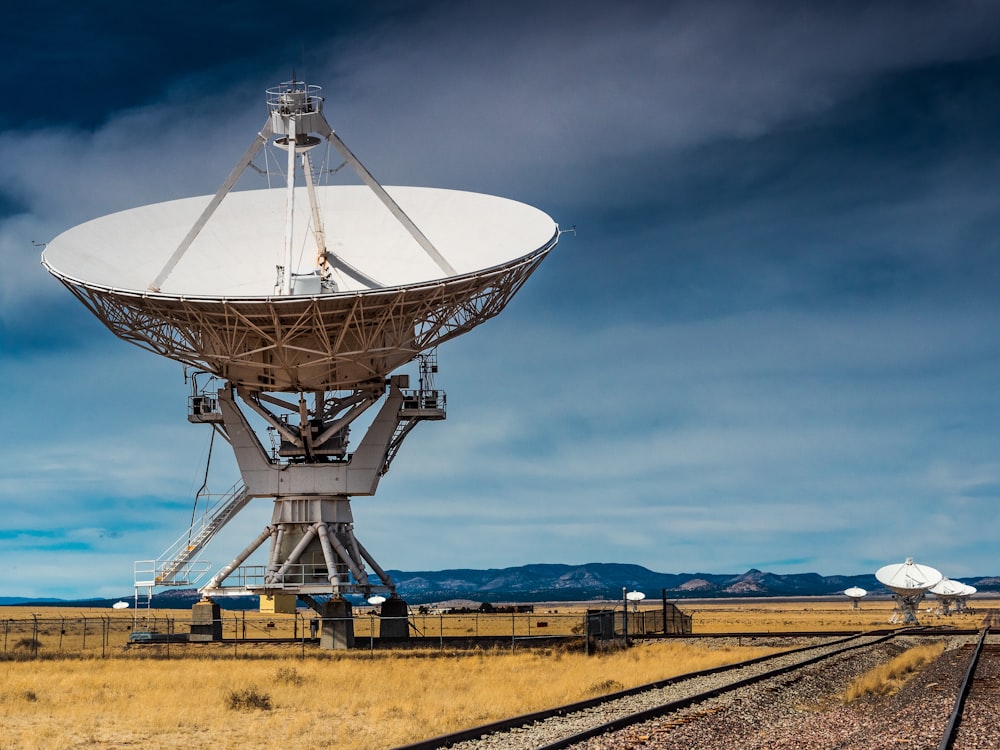 una antena parabólica muy grande en la parte superior de una vía de tren