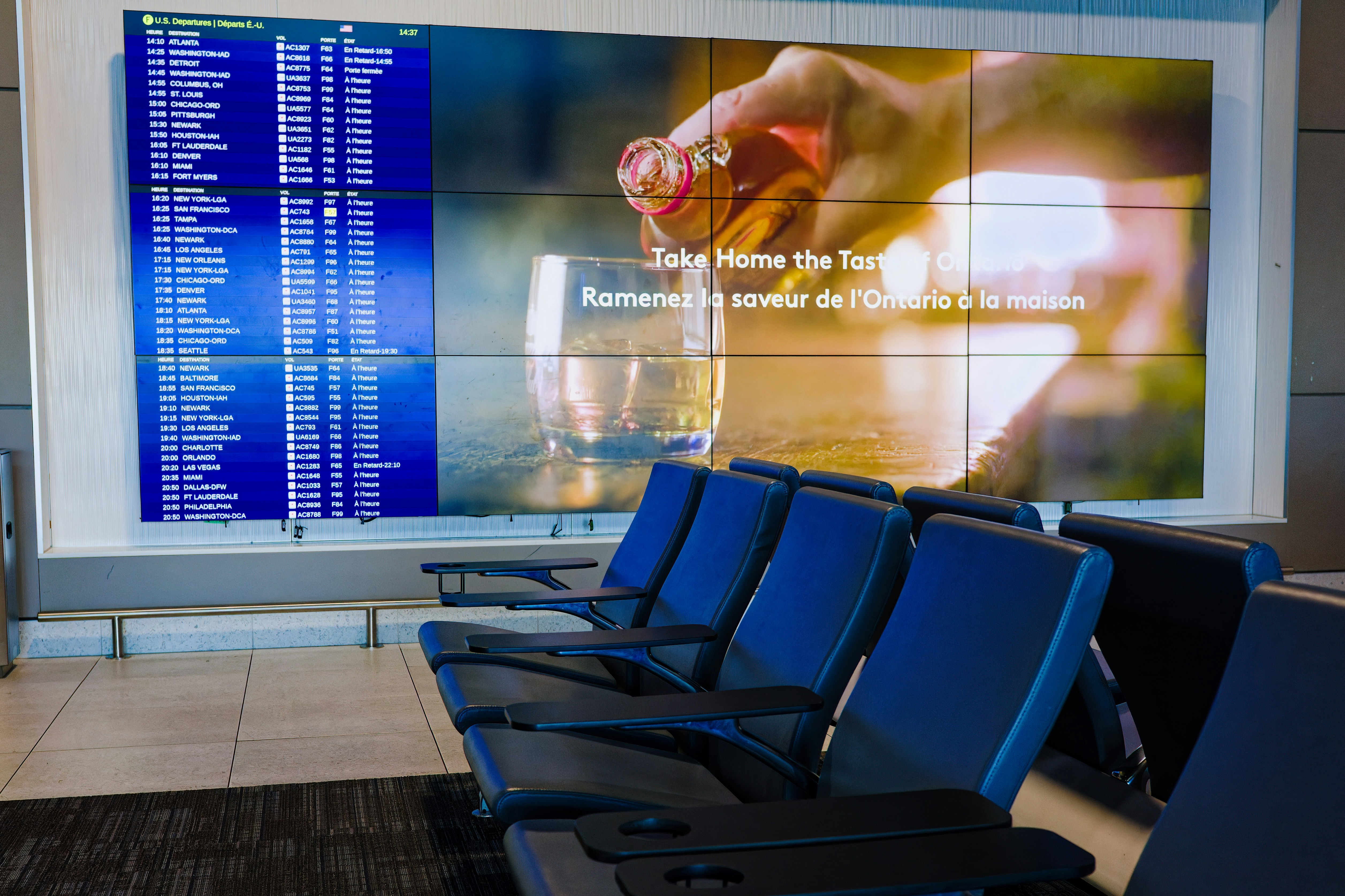 a row of blue chairs sitting in front of a large screen