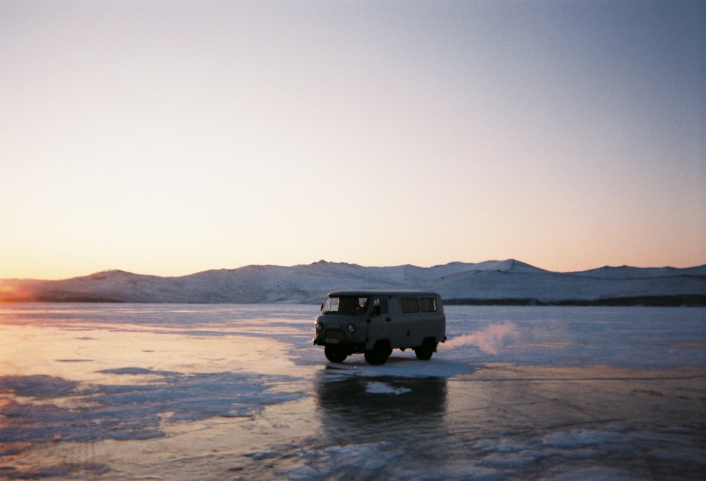 a van driving across a frozen lake at sunset