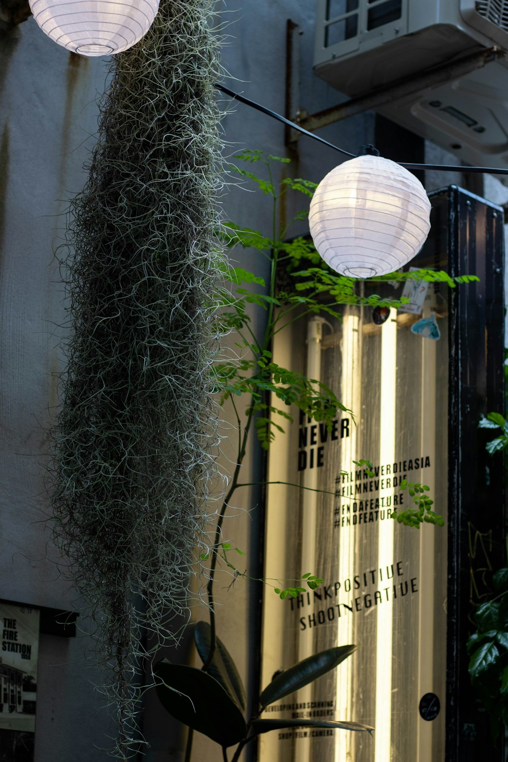 a couple of white paper lanterns hanging from the side of a building