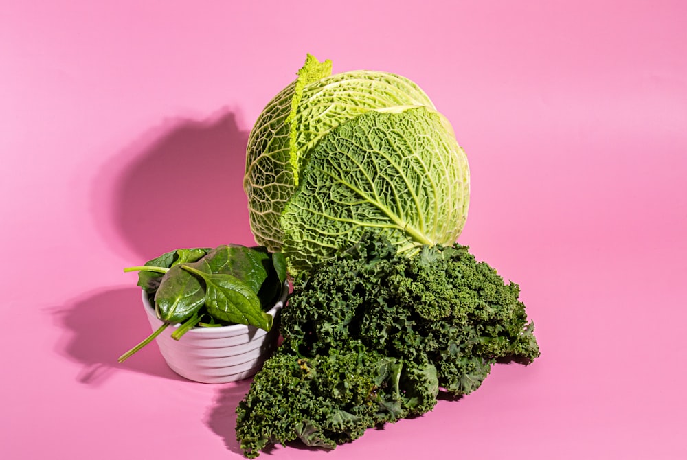 a head of cabbage next to a bowl of broccoli