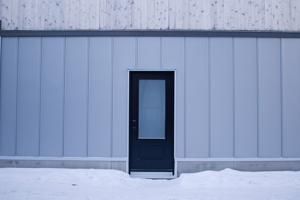 a black door is in the middle of a snowy area