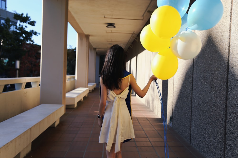 a woman holding a bunch of balloons in her hand