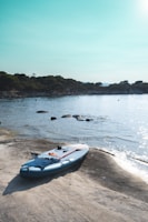 A paddleboard resting on the shore next to the campervan.