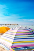 Colorful beach umbrellas lining the shore under a clear sky.