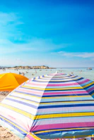 Candid shot of the beach crew setting up colorful umbrellas under a bright blue sky