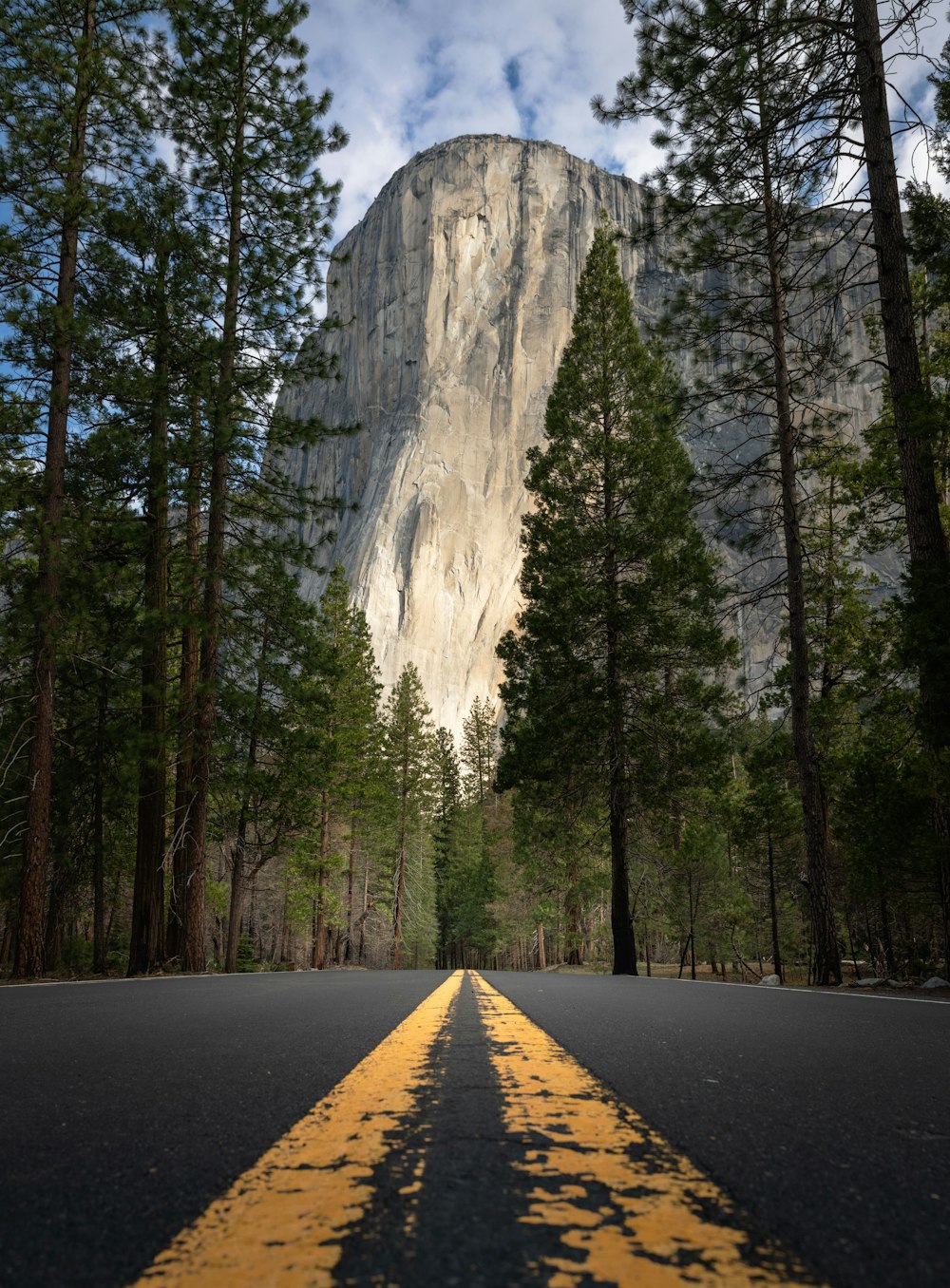 a yellow line on a road in front of a mountain