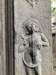 An ancient temple carving depicting Shiva with his trident and crescent moon.