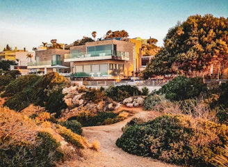 A sleek, modern villa with large windows and a landscaped garden at sunset.