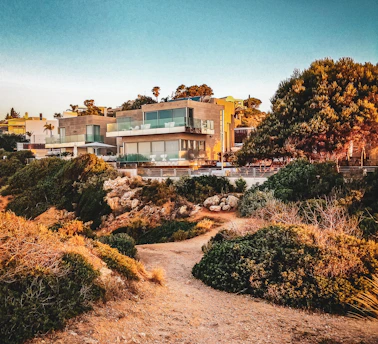 A sleek, modern villa with large windows and a landscaped garden at sunset.