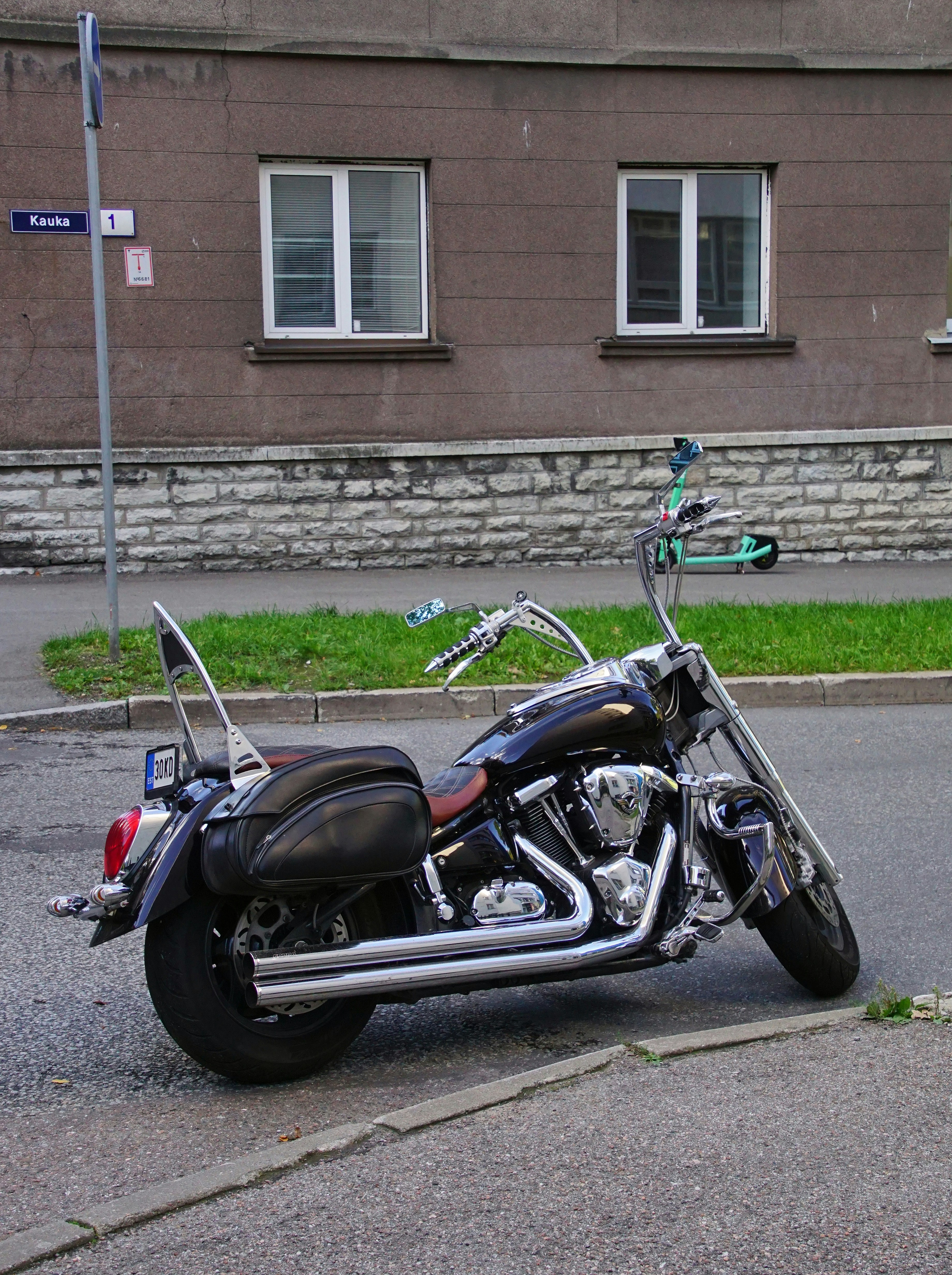 Black cruiser motorcycle parked on dark asphalt, low-angle shot, dramatic side lighting, metallic chrome details gleaming, deep shadows, moody industrial atmosphere