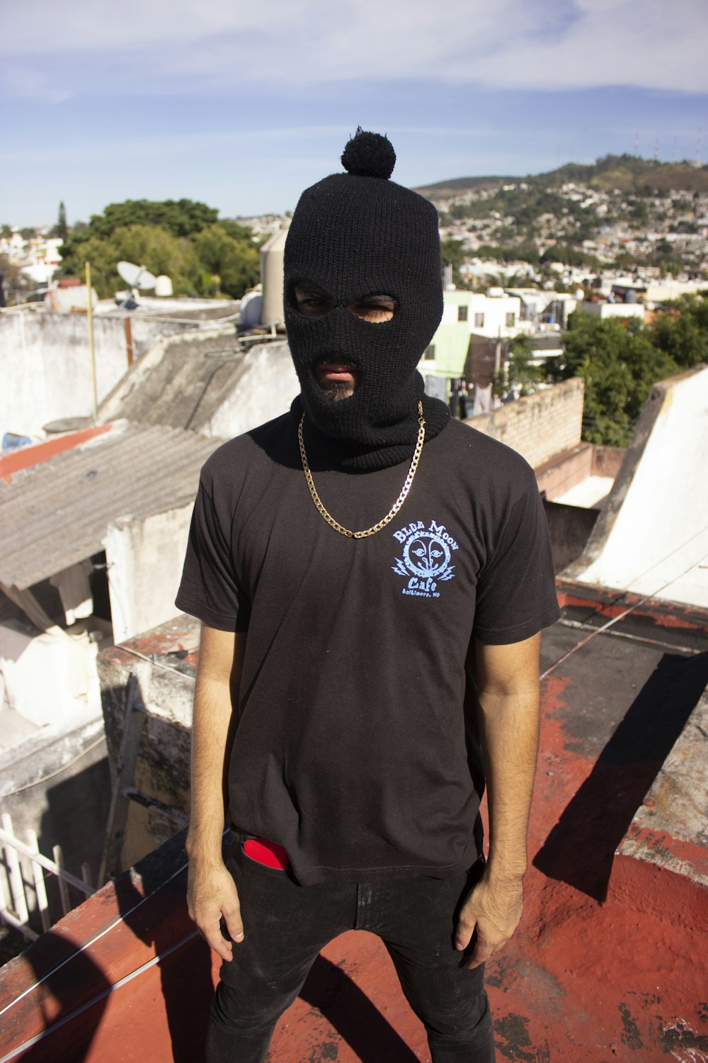 a man wearing a black mask standing on top of a roof