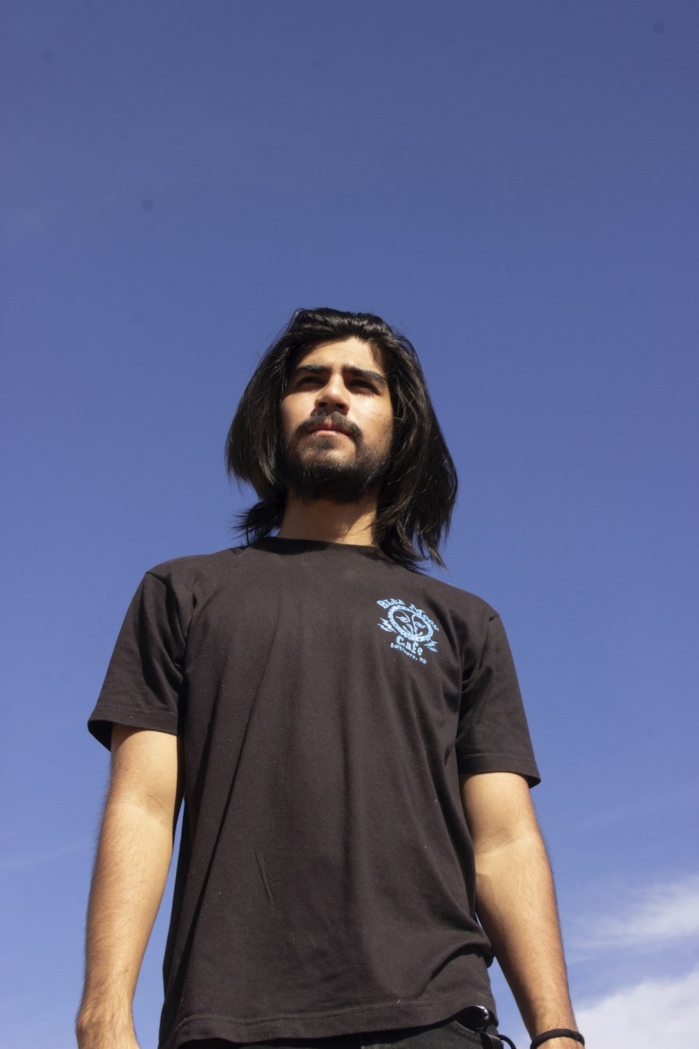 a man with long hair standing in front of a blue sky