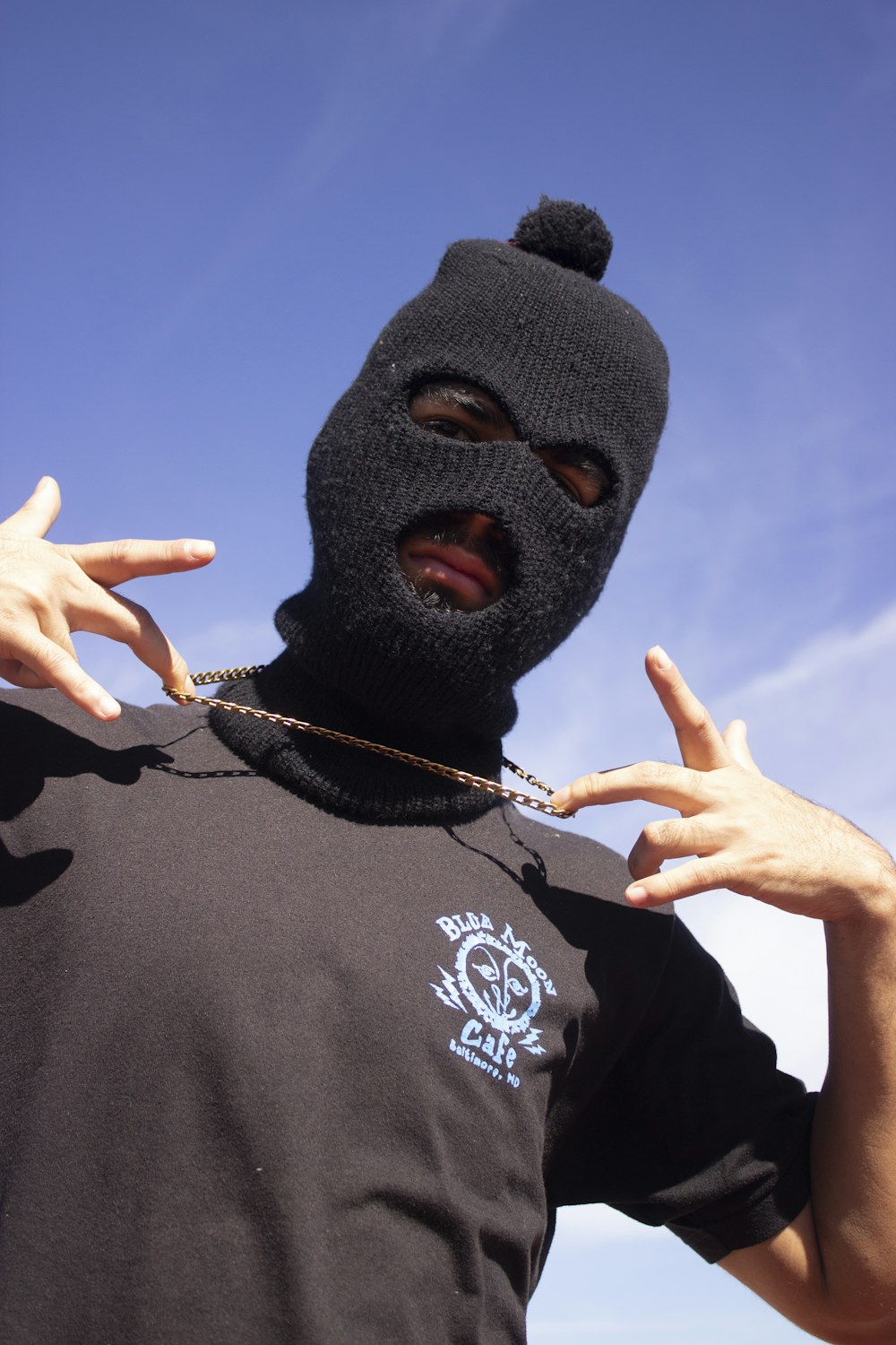 a man wearing a black mask with his hands in the air