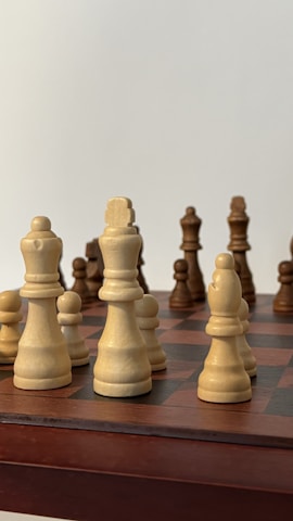 Close-up of chess pieces arranged strategically on a wooden chessboard.