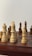 A close-up view of a chessboard displaying several wooden chess pieces in an ongoing game. The pieces are arranged on a classic checkered board, with a mix of light and dark colored pieces.