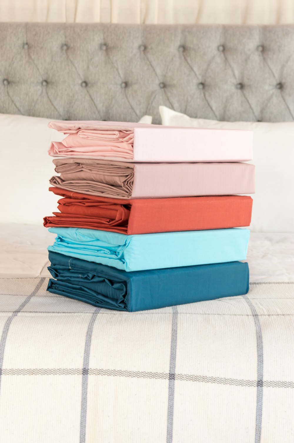 a stack of folded sheets sitting on top of a bed