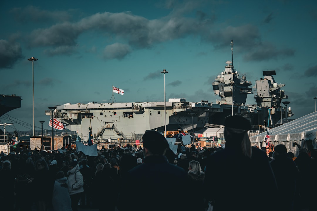 a crowd of people standing in front of a large ship, HMS Prince Of Wales