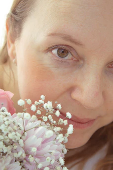 A serene close-up of Kimberly smiling softly, surrounded by delicate pink roses.