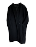 A long black coat featuring a minimalist design with a single-breasted button closure. The coat has two large front pockets and appears to be made of a heavy fabric suitable for colder weather.