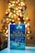 A book titled 'The Christmas Wish' by Nora Roberts is prominently displayed in the foreground, resting on a flat surface. The background features a warmly lit Christmas tree adorned with lights and ornaments, creating a cozy and festive atmosphere.