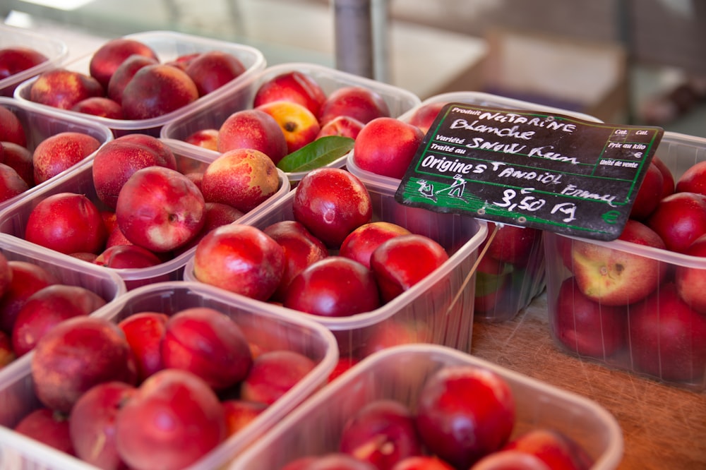 a table topped with plastic containers filled with red apples