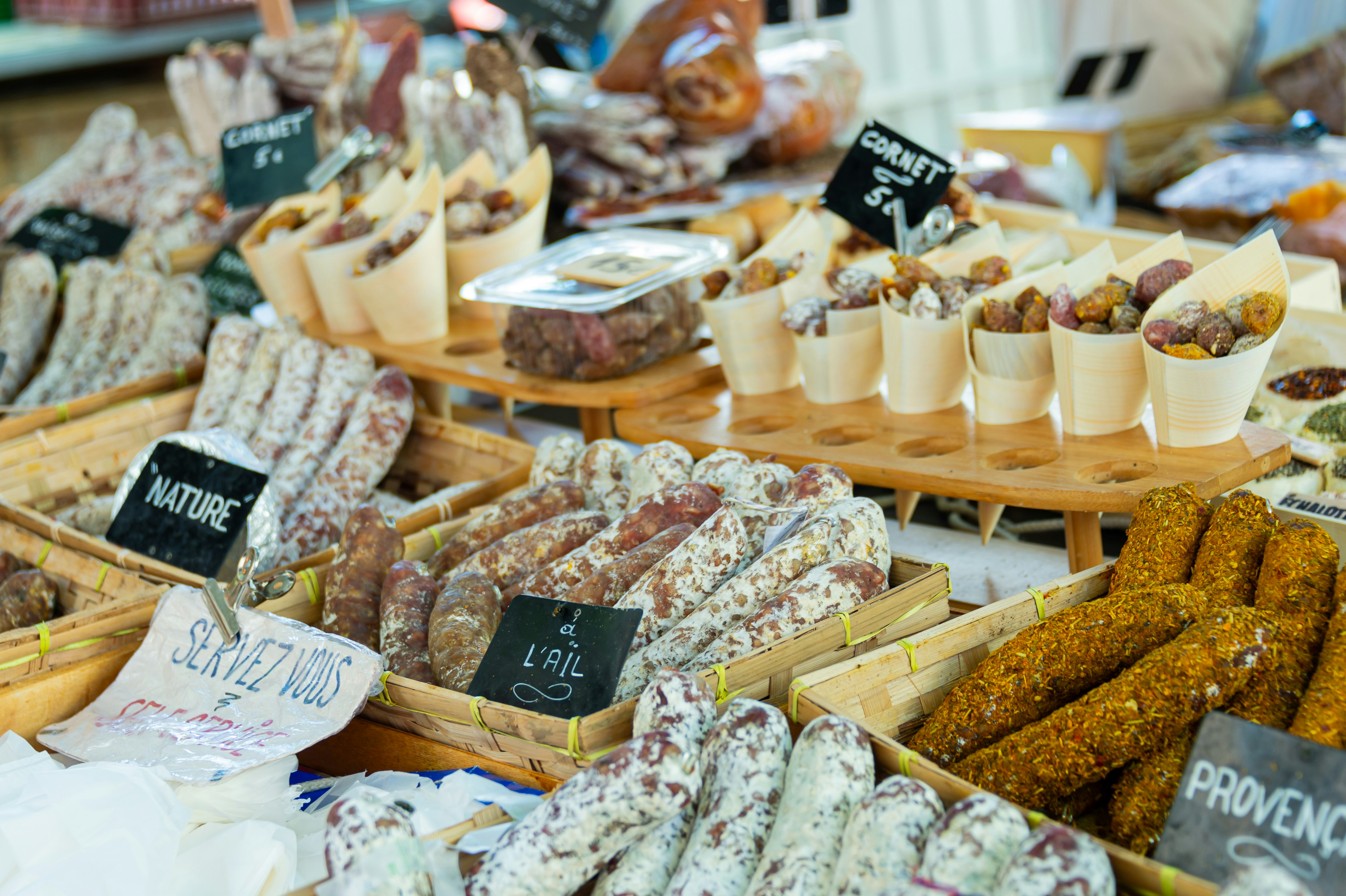 Baskets of fresh cheese, meats, nuts, and dried fruits at an open-air market in Aix-en-Provence, France.