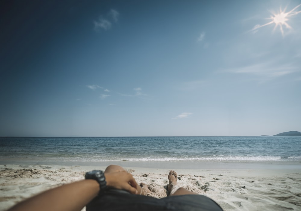uma pessoa deitada na areia de uma praia