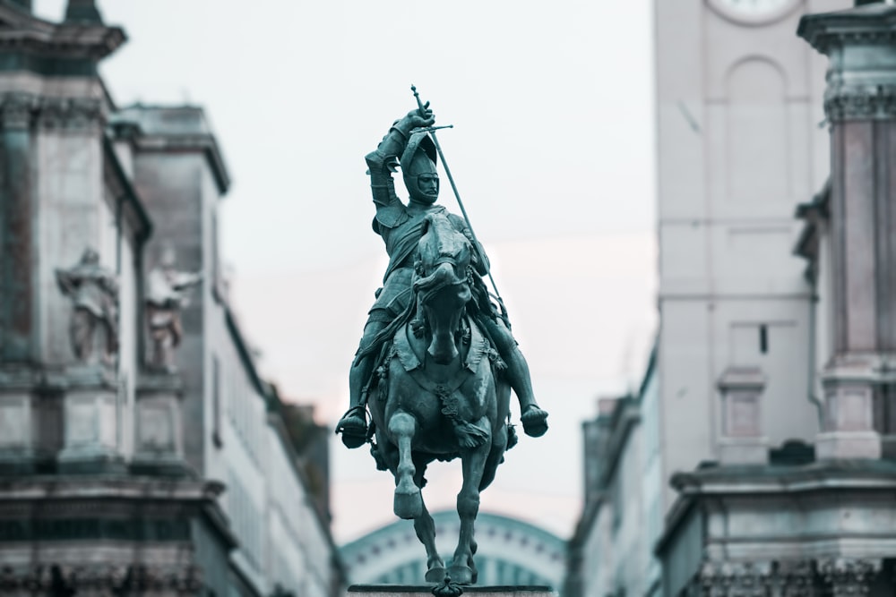 uma estátua de um homem montado em um cavalo em frente a uma torre do relógio