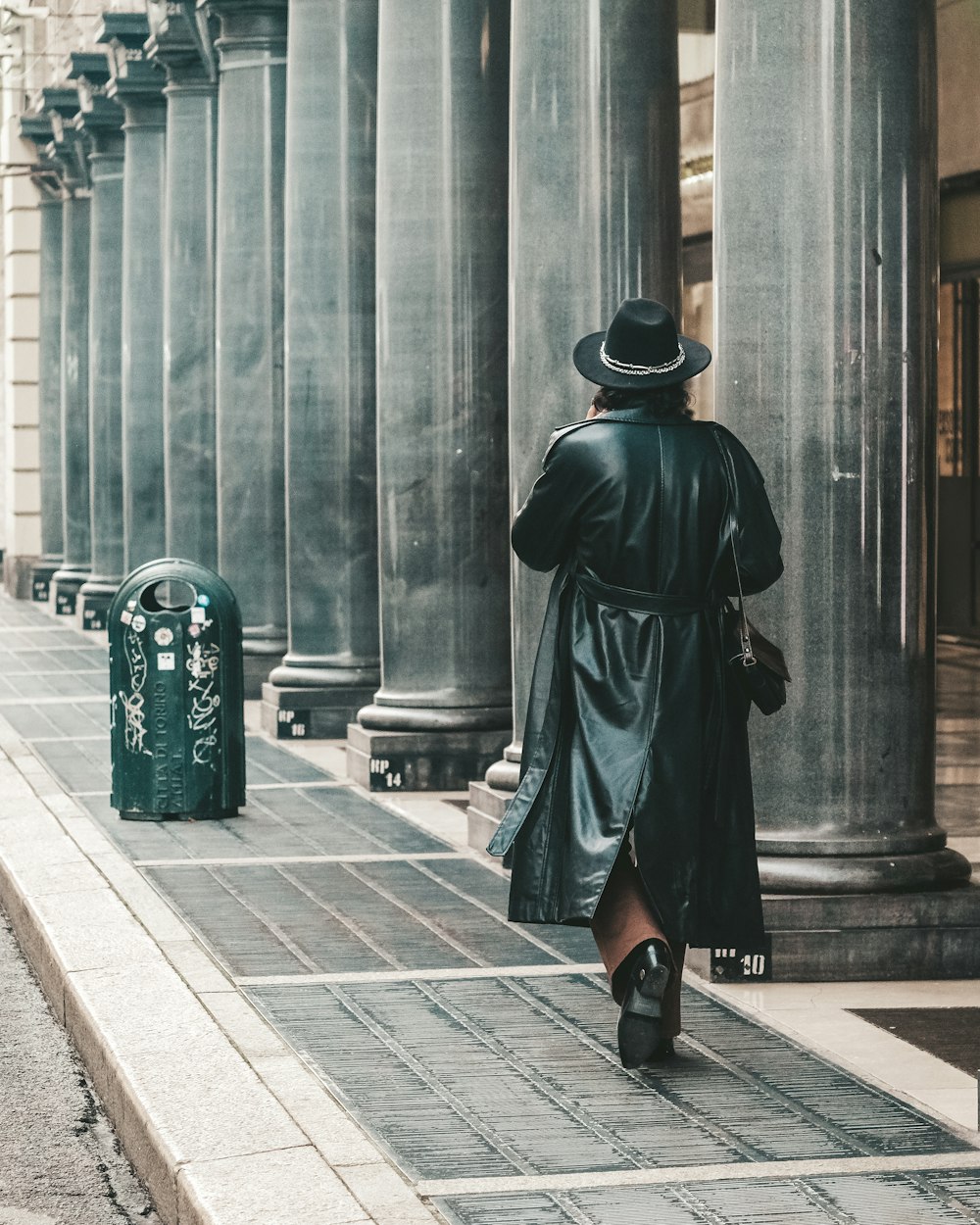 a woman walking down a street next to tall pillars