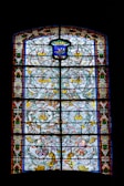A stained glass window featuring the family crest in vibrant colors.