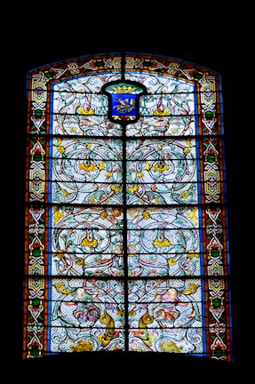 A stained glass window featuring the family crest in vibrant colors.
