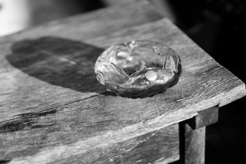 Close-up of a unique upcycled glass ashtray with natural wood details on a black background.