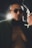 A person wearing sunglasses and headphones is holding a cigarette. The lighting creates a dramatic effect with shadows and highlights, and smoke curls upwards in the background.