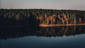 A calm lake reflecting autumn trees in vibrant reds and oranges.