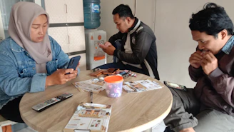 A group of diverse Muslim community members engaging happily around a digital device.