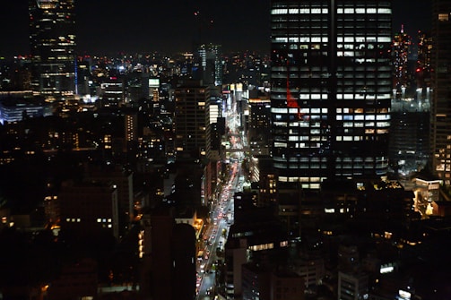 A bustling city skyline at night with illuminated skyscrapers and busy streets.