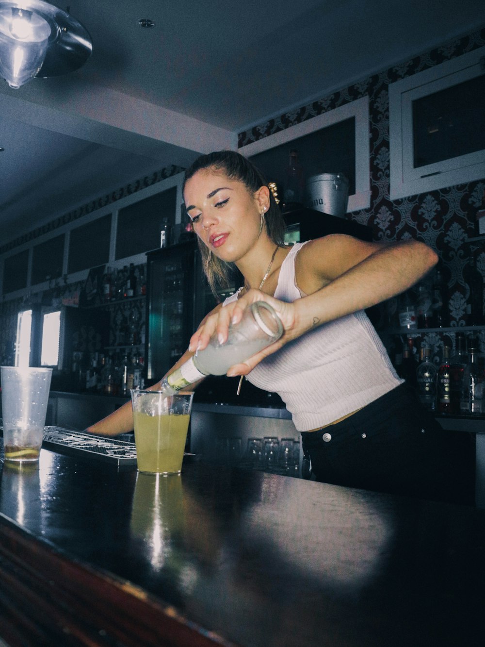 a woman pouring a drink into a glass