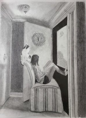 An intimate moment of an artist sketching while a cat naps beside them.