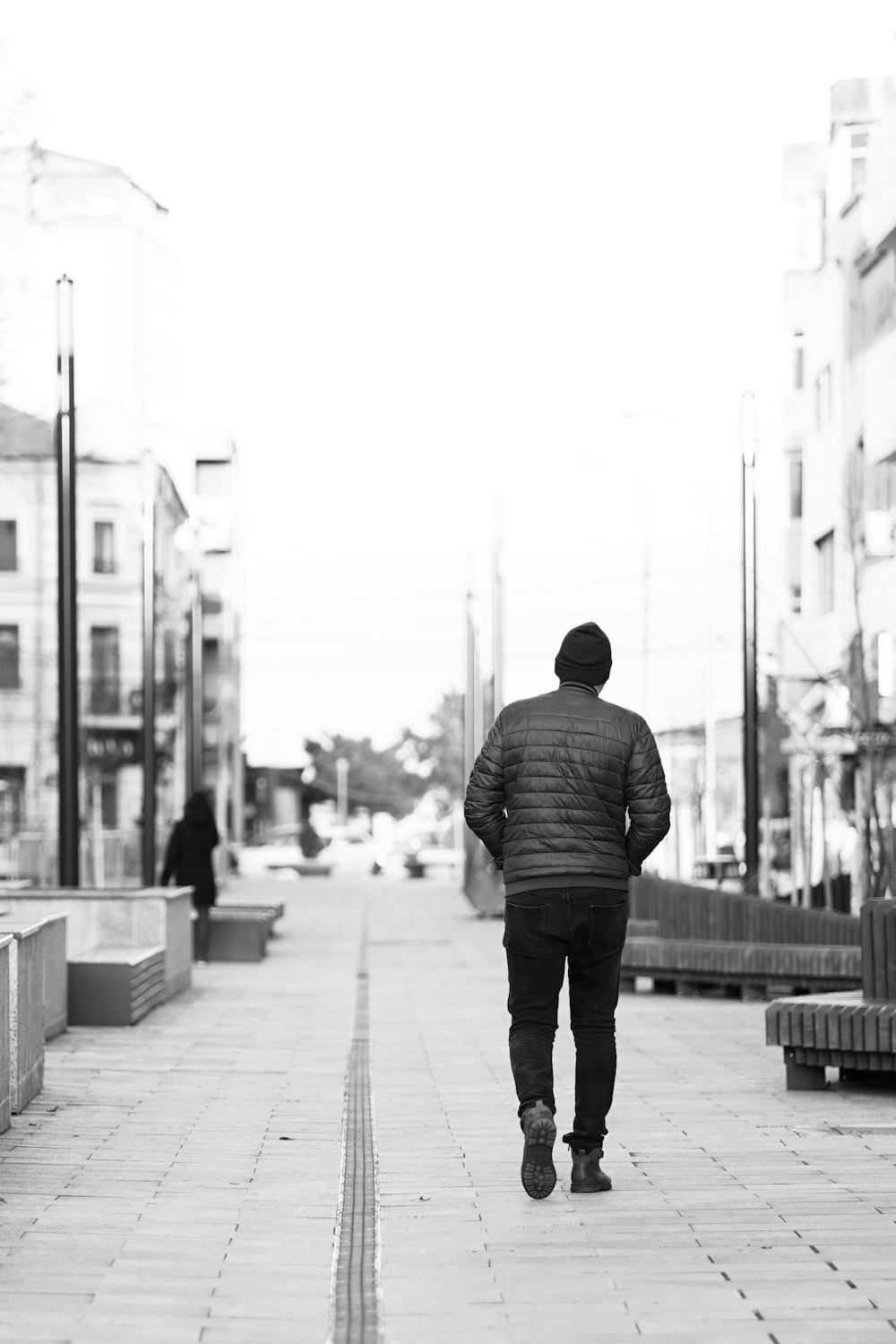 a man walking down a sidewalk in a black and white photo