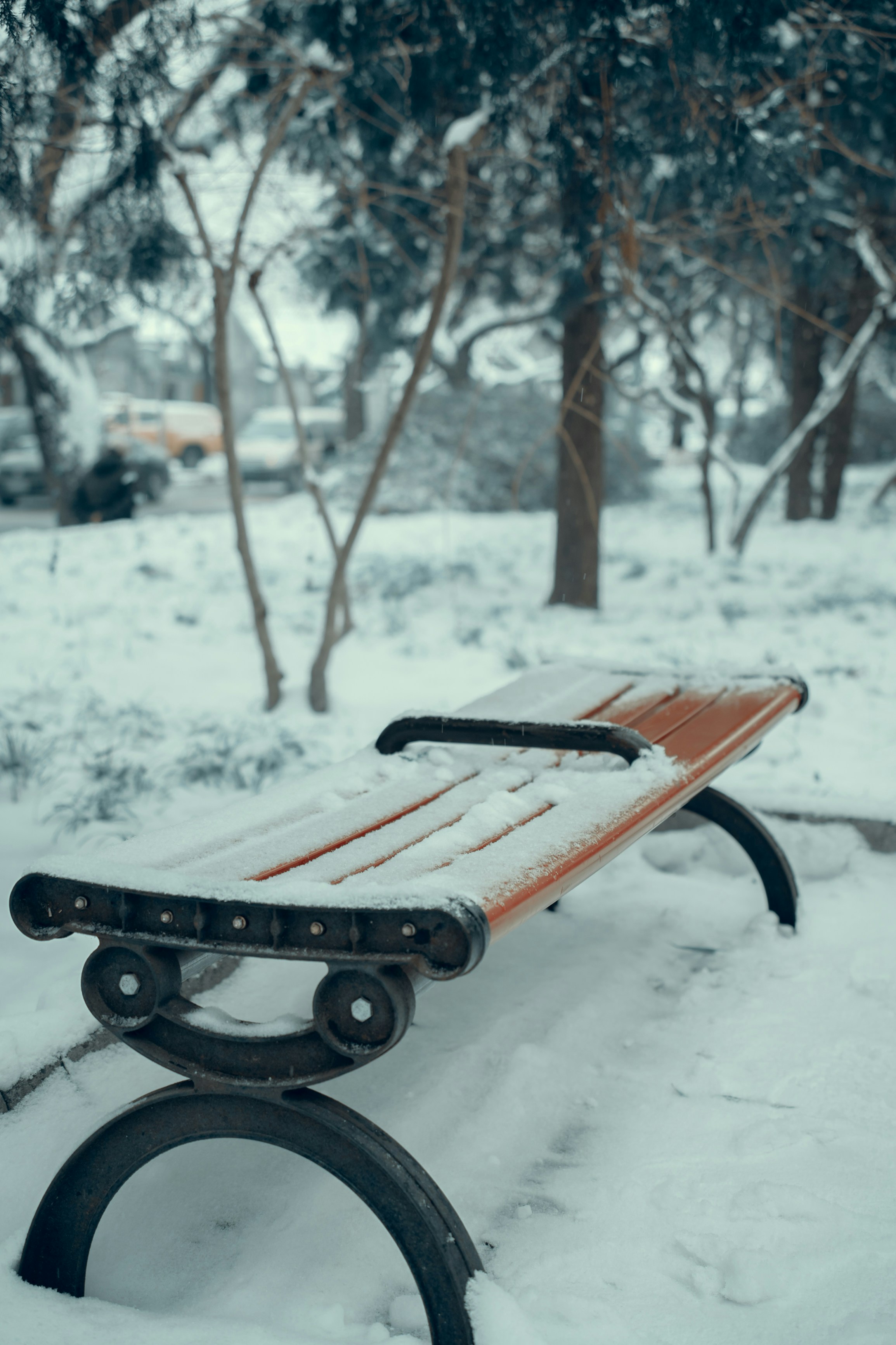 a wooden bench covered in snow in a park