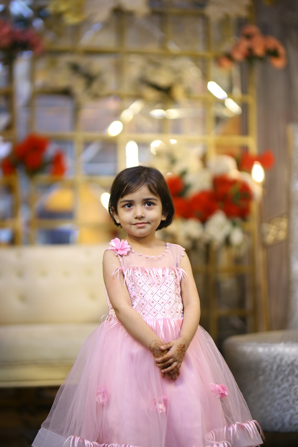 a little girl in a pink dress posing for a picture