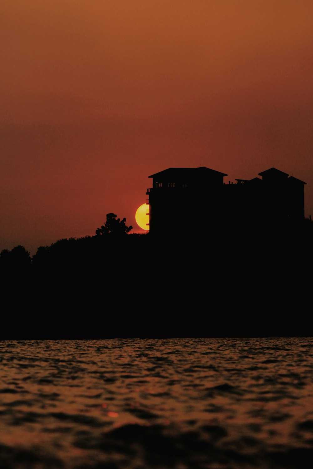 el sol se está poniendo sobre una casa en una colina