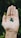A hand is open with three small, round green pills or beads resting on the palm against a blurred, leafy background.