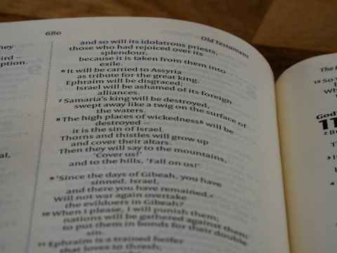 A close-up view of an open book displaying text from the Old Testament. The page is slightly curved with text that includes chapter and verse numbers. The paper color is off-white, and the text is in black.
