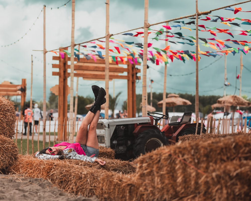 a woman laying on top of a pile of hay