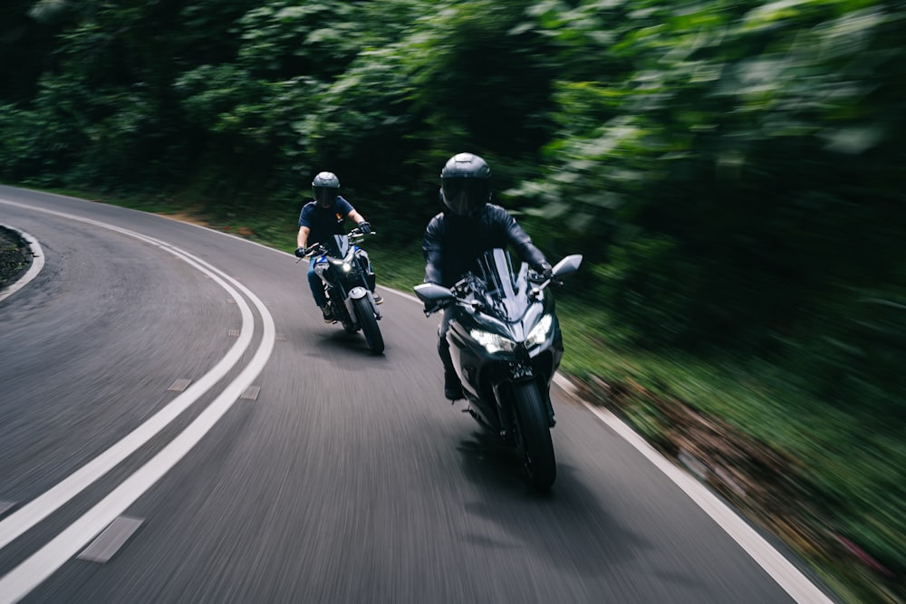 two people riding motorcycles down a curvy road