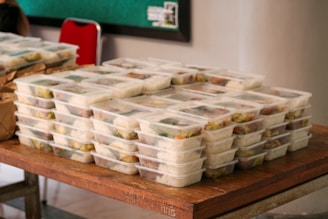 a table topped with plastic containers filled with food